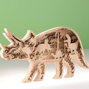 May include: A wooden, layered Triceratops sculpture. The light brown dinosaur features intricate cutouts revealing a prehistoric landscape with other dinosaurs and foliage. The sculpture stands on four legs with a detailed head and horns.