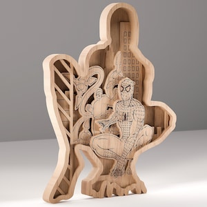 Op de afbeelding: Een houten, gelaagde sculptuur met Spider-Man in een hurkende pose, met een stadsgezicht en andere personages op de achtergrond. Het kunstwerk is gesneden uit lichtgekleurd hout en toont ingewikkelde details.