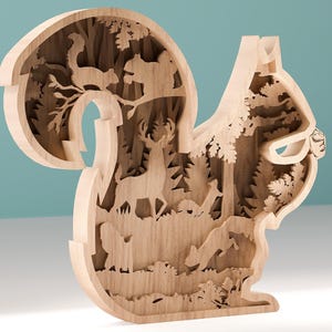Op de afbeelding: Een houten eekhoornsculptuur met uitgesneden bosscènes in lagen. Het ontwerp bevat eekhoorns, herten, bomen en andere bos elementen. De natuurlijke houtkleur benadrukt de ingewikkelde details van het lasergesneden ontwerp.