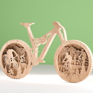 May include: A wooden mountain bike sculpture with intricate cutouts. The wheels feature scenes of cyclists riding through a mountain landscape with trees and peaks. The bike is made of light-colored wood and stands against a green background.