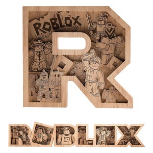 Puede incluir: Pieza de arte de madera en capas con la palabra "ROBLOX" y la letra "R" con personajes grabados. Los personajes son del juego Roblox. La pieza de arte está hecha de madera de color claro.