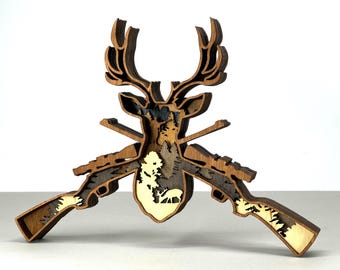 May include: A layered wooden art piece featuring a deer head with antlers, two rifles, and a forest scene. The artwork is primarily brown with lighter wood accents, creating a three-dimensional effect. The design is suitable for rustic or hunting-themed decor.