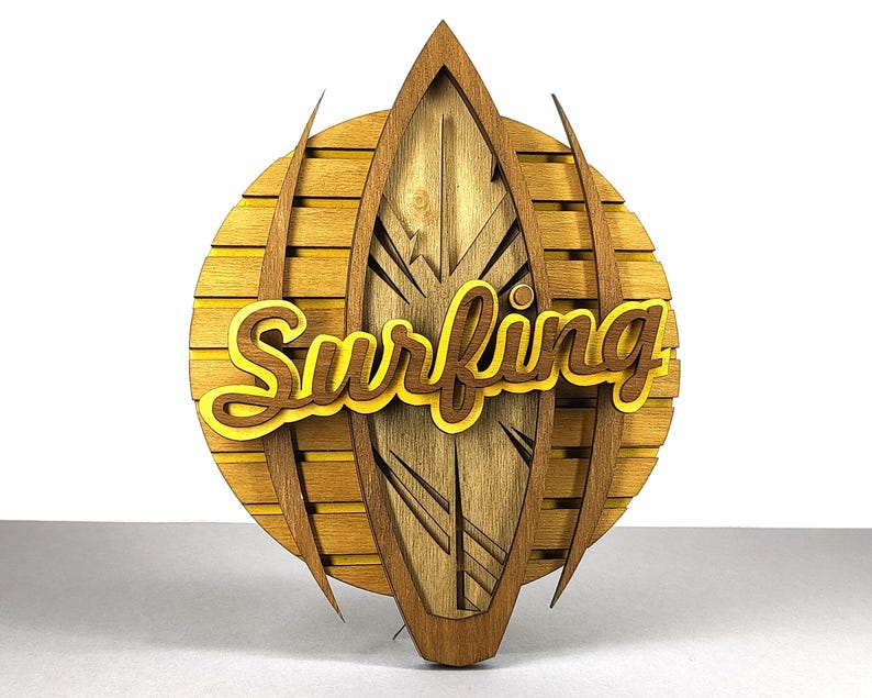 May include: Wooden wall art featuring a surfboard design with the word "Surfing" in yellow and brown. The surfboard is set against a circular background with horizontal wooden slats. The overall design is a warm, natural color.