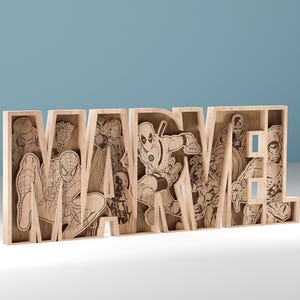 以下が含まれることがあります： マーベルのスーパーヒーローの彫刻が施された木製の「MARVEL」サイン。サインは明るい色の木材で作られており、3次元のデザインです。背景は無地の水色です。