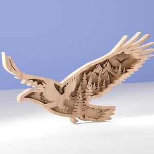 Może przedstawiać: Drewniana rzeźba orła w locie, z warstwowym wzorem przedstawiającym krajobraz gór i lasów w skrzydłach. Orzeł jest jasnobrązowy, ze szczegółowymi wycięciami. Tło to gradient bieli i błękitu.