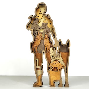 May include: A layered wooden art piece depicting a person with dogs. The artwork features a person with dogs, and a dog-like figure. The piece is made of various shades of brown wood, creating a 3D effect.