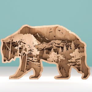 Puede incluir: Pieza de arte de madera con forma de oso con un diseño en capas. El interior presenta una cordillera, árboles y pájaros, todos tallados en la madera. El oso está caminando, con sus patas visibles. La pieza es de madera marrón claro.