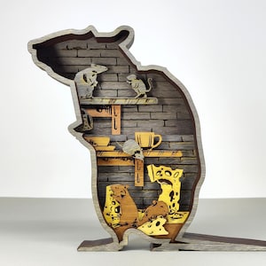 May include: A wooden, layered art piece in the shape of a rat, featuring a detailed interior scene. The interior shows a brick wall, shelves, and small mice figures. The color palette includes shades of brown, gray, and yellow.