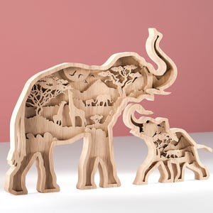 Pode incluir: Escultura de madeira de uma família de elefantes com um design em camadas. O interior apresenta uma cena de savana com girafas, árvores e outros animais. A escultura é feita de madeira clara e está sobre um fundo rosa.