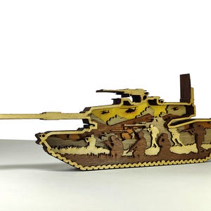 Puede incluir: Maqueta de tanque de madera con un cañón largo y un diseño intrincado en capas. El modelo presenta varios tonos de marrón y amarillo, con siluetas de soldados en el interior. El tanque está sobre un fondo blanco.