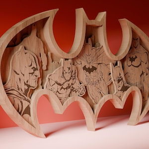May include: Wooden Batman logo wall art featuring multiple Batman illustrations. The artwork is made of layered wood, creating a 3D effect. The design showcases various depictions of Batman in a natural wood finish.
