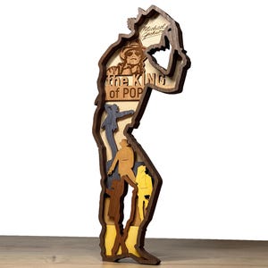 Peut inclure: Sculpture en bois multicouche de Michael Jackson en silhouette, avec le texte "the KING of POP" et "Michael Jackson". La sculpture présente différentes couches colorées et est conçue pour tenir debout.