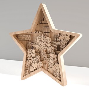 Puede incluir: Arte de pared en forma de estrella de madera con un dise&ntilde;o en capas que representa personajes y elementos de la serie de videojuegos Super Mario. La obra de arte incluye a Mario, Bowser, la Princesa Peach y otras figuras ic&oacute;nicas, todas cortadas con l&aacute;ser de madera clara.