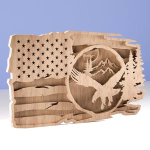 May include: Wooden artwork depicting the American flag with a carved design of an eagle, mountains, and trees. The flag shows stars and stripes, with the eagle in a circular frame. The wood has a natural finish.