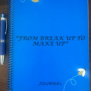 Pode incluir: Caderno azul de espiral com o texto "FROM BREAK UP TO MAKE UP" e a palavra "JOURNAL" na parte inferior. A capa tem um desenho de abelha com corpo amarelo e listras pretas.