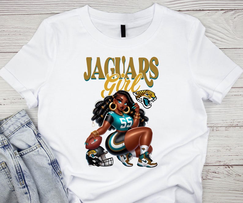 Pu&ograve; includere: T-shirt bianca con un'illustrazione a cartoni animati di una donna in uniforme da football turchese e nera, numero 55. Il testo "Jaguars Girl" &egrave; sopra l'illustrazione, insieme a un logo di giaguaro e un pallone da football.
