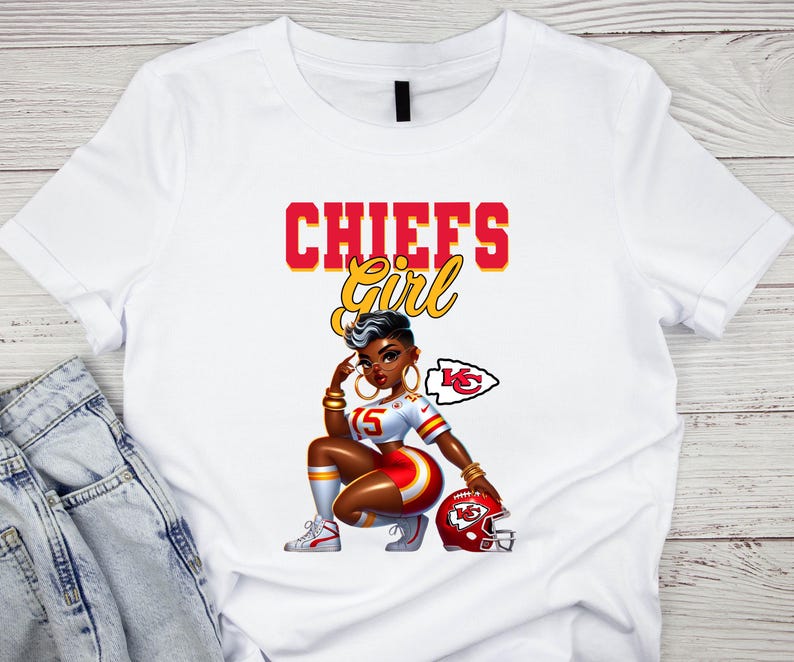 Pu&ograve; includere: T-shirt bianca con grafica di una donna in uniforme da football dei Chiefs, con la scritta "CHIEFS Girl" in rosso e giallo. La donna indossa un'uniforme rossa e bianca, gioielli dorati e tiene in mano un casco rosso.