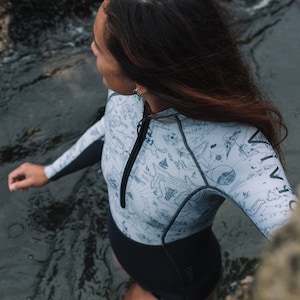 Woman wild swimming in a river wearing the reversible 2mm recycled neoprene springsuit women's shorty wetsuit for surfing & swimming