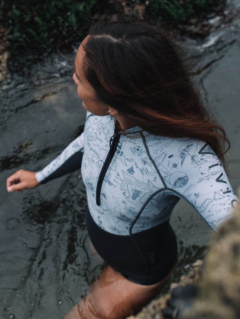 Woman wild swimming in a river wearing the reversible 2mm recycled neoprene springsuit women's shorty wetsuit for surfing & swimming