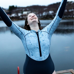 Woman by an icy lake wearing the reversible 2mm recycled neoprene springsuit women's shorty wetsuit for surfing & swimming