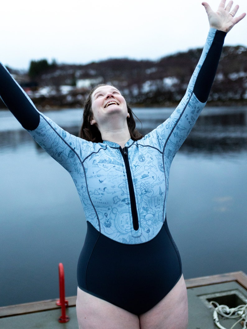 Woman by an icy lake wearing the reversible 2mm recycled neoprene springsuit women's shorty wetsuit for surfing & swimming