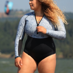 Woman by a lake wearing the reversible 2mm recycled neoprene springsuit women's shorty wetsuit for surfing & swimming
