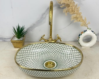 May include: Oval ceramic sink with a green and white geometric pattern and a gold rim. The sink has a drain in the center.