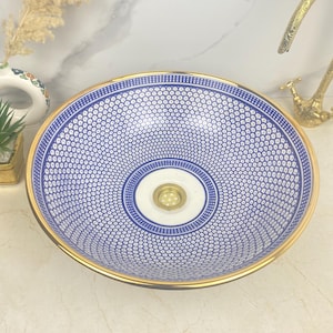 Peut inclure: Un lavabo en céramique bleu et blanc avec une bordure dorée. Le lavabo a un design circulaire avec un centre blanc et un anneau extérieur bleu. Le lavabo est parfait pour une salle de bain moderne.