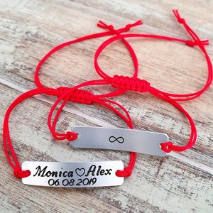 Pu&ograve; includere: Due braccialetti abbinati con cordini rossi e targhette rettangolari argentate. Uno ha il simbolo dell'infinito, l'altro i nomi "Monica" e "Alex" con un cuore e la data "06.08.2019".