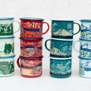 May include: A set of ten enamel mugs with different designs featuring national parks. The mugs are stacked in three groups of three and one group of four. The designs include Mount Rainier National Park, Olympic National Park, and Mount Hood National Forest.