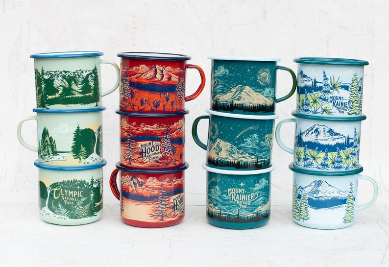 May include: A set of ten enamel mugs with different designs featuring national parks. The mugs are stacked in three groups of three and one group of four. The designs include Mount Rainier National Park, Olympic National Park, and Mount Hood National Forest.