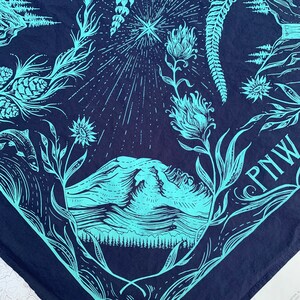 May include: A blue bandana featuring a mountain range, a star, and floral designs. The text "PNW" is printed in the bottom right corner.