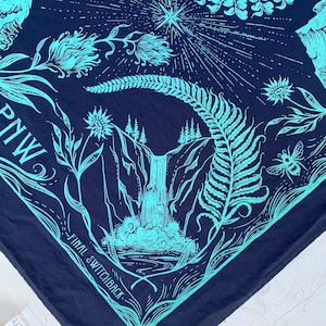 May include: A blue bandana with a teal design of a waterfall, ferns, and flowers. The text "FINAL SWITCHBACK" and "PNW" are printed on the bandana.