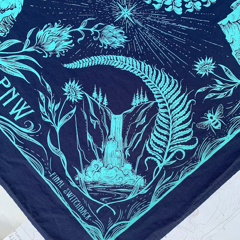 May include: A blue bandana with a teal design of a waterfall, ferns, and flowers. The text "FINAL SWITCHBACK" and "PNW" are printed on the bandana.