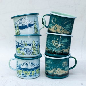 May include: A stack of six enamel mugs with a blue and green color scheme. The mugs feature a mountain scene with the text "Mount Rainier National Park".