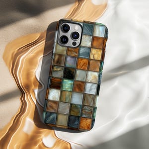 Puede incluir: Una funda para smartphone con un diseño de mosaico. La funda presenta una cuadrícula de pequeñas baldosas cuadradas en tonos marrones, naranjas, azules y blancos. La funda tiene un acabado brillante y un recorte para la cámara.
