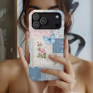 May include: A smartphone case featuring a patchwork design of light blue, pink, and white floral patterns. The case includes a central illustration of a pink rose and a single light blue butterfly, with a camera cutout at the top left corner.