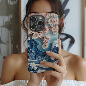 May include: A phone case with a blue and white wave design and pink flowers. The case is made of a textured material and has a raised design.