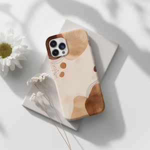 May include: A phone case with an abstract design in shades of brown and beige. The case features a pattern of organic shapes, lines, and dots. The camera area is a darker brown. The case is resting on a white surface.