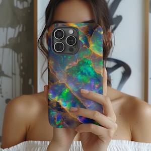 以下が含まれることがあります： 虹色のオパール模様の携帯電話ケース。ケースには、3つのレンズが付いた黒いカメラの突起があります。