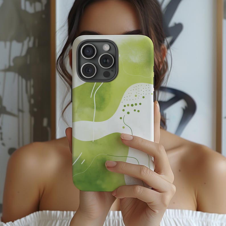 May include: A green and white phone case with an abstract design. The case has a camera lens cutout and a white background with green abstract shapes.
