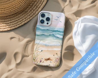 May include: A phone case with a beach scene design. The case features a watercolor painting of ocean waves, a sandy shore, and small flowers. The case is light pink and has a MagSafe Compatible label.