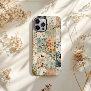 May include: A phone case featuring a floral patchwork design. The case is cream-coloured with a variety of flowers and leaves in shades of pink, blue, and green. The case has a cutout for the phone's camera.