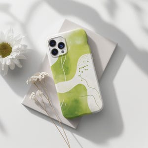 May include: A green and white phone case with an abstract design. The case has a white background with green watercolor-like shapes and lines. The phone case has a camera lens cutout.