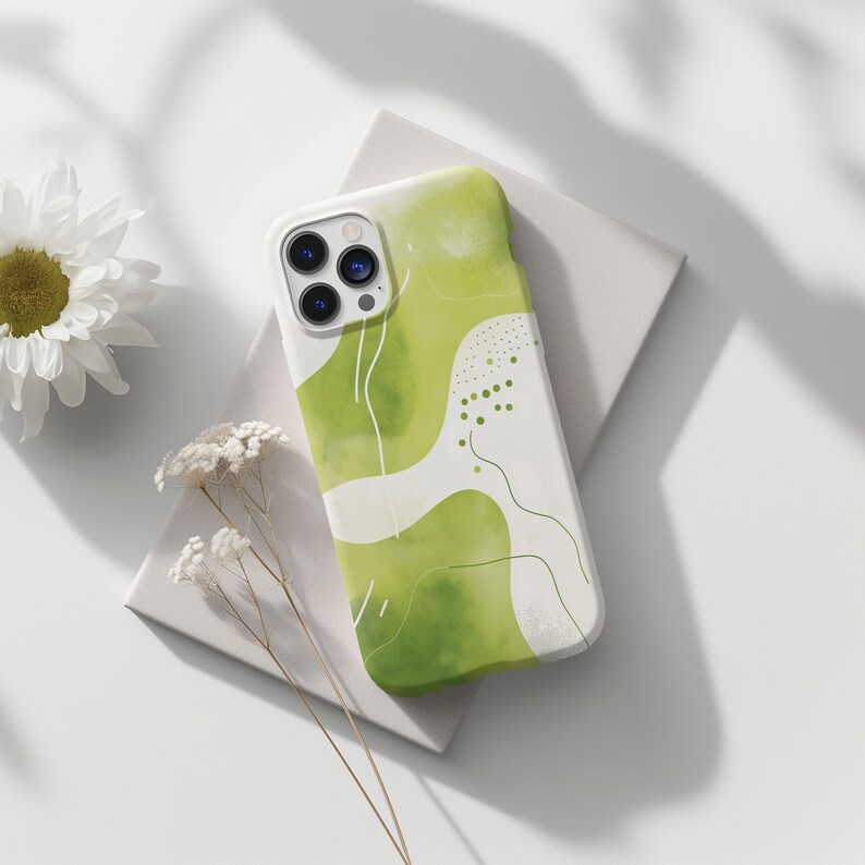 May include: A green and white phone case with an abstract design. The case has a white background with green watercolor-like shapes and lines. The phone case has a camera lens cutout.