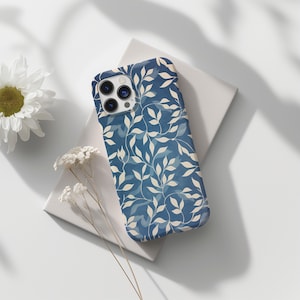 May include: A blue phone case with a white floral pattern. The case has a cutout for the camera lens.