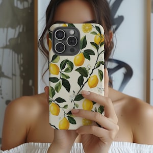 May include: A white phone case with a lemon print. The case has a cream background with green leaves and yellow lemons. The phone case has a camera lens cutout.