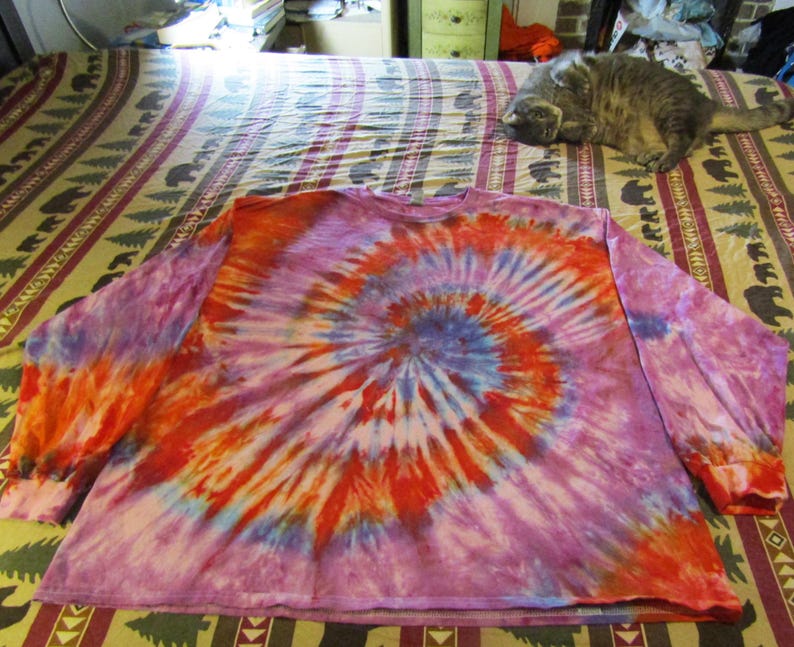 May include: A long-sleeved tie-dye shirt with a swirling pattern in shades of pink, orange, blue, and white.
