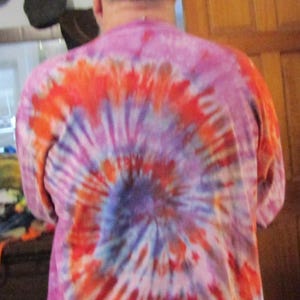 May include: A pink, orange and blue tie-dye shirt with a swirling pattern.
