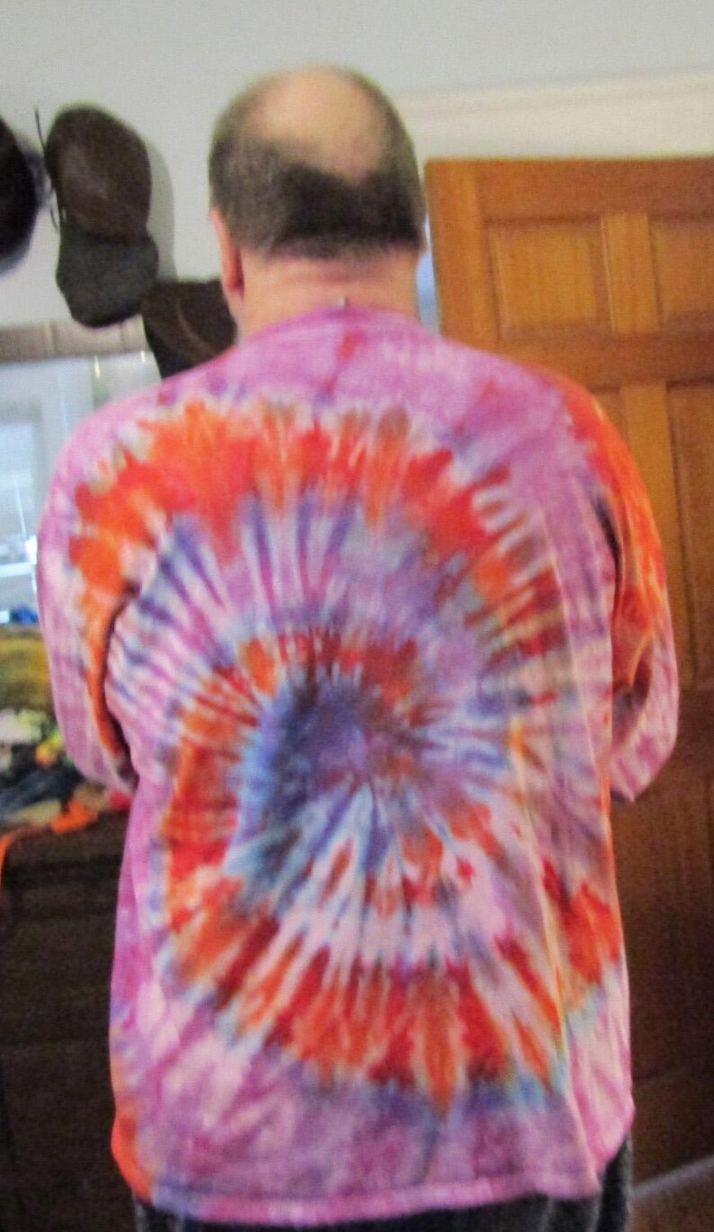 May include: A pink, orange and blue tie-dye shirt with a swirling pattern.